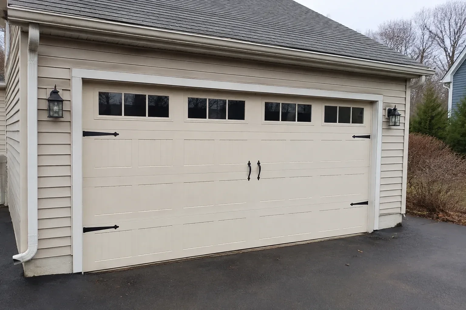 Cream carriage-house-style garage door with dark decorative hardware. — Carriage-House Garage Door Installation, Hamilton